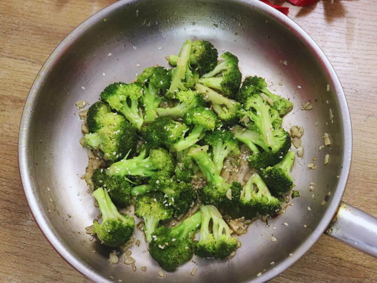 Mediterranean broccoli cooked in a pan placed on a brown countertop.