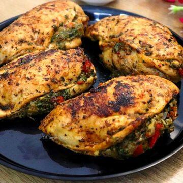 close-up of 4 mediterranean stuffed chicken. Juicy chicken breast stuffed with spinach, bell peppers, garlic, feta cheese, and herbs.