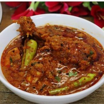 close-up of achari chicken served in a white bowl.